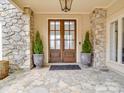 Elegant stone entryway with double doors, decorative plants, and a stone patio at 503 Stuart Rdg, Cramerton, NC 28032