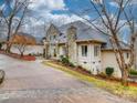 Stately home featuring a stone chimney and accents, complimented by a circular driveway and mature trees at 503 Stuart Rdg, Cramerton, NC 28032