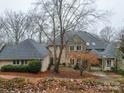 Spacious home with a stone chimney, complimented by a circular driveway and mature trees in a lush landscape at 503 Stuart Rdg, Cramerton, NC 28032