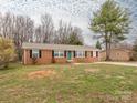 Charming brick home featuring a manicured lawn, black shutters and a brightly painted front door at 608 E Matthews St, Matthews, NC 28105