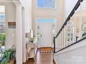 Bright foyer with wood floors, console table, staircase, and transom window above the door at 9906 Mitchell Glen Dr, Charlotte, NC 28277