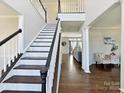 Inviting foyer features hardwood floors, staircase with black handrail, and views into the living room at 9906 Mitchell Glen Dr, Charlotte, NC 28277