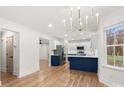Modern kitchen featuring an island with a navy blue base, stainless steel appliances, and hardwood flooring at 130 Valley Glen Dr, Troutman, NC 28166