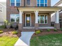 Inviting front porch with brick supports, stone walkway, and manicured landscaping at 17021 Malone Ln, Mint Hill, NC 28227