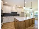 Bright kitchen featuring an island, white cabinets, modern backsplash, and pendant lights at 17021 Malone Ln, Mint Hill, NC 28227