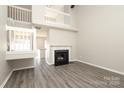 Bright living room with a fireplace, grey toned flooring, a high ceiling and a view of the staircase and entry to the kitchen at 7725 Petrea Ln, Charlotte, NC 28227
