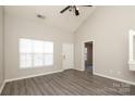 Spacious, naturally lit living room featuring vaulted ceilings, grey tone flooring, and a view of the front door at 7725 Petrea Ln, Charlotte, NC 28227