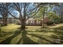 Charming brick home with lush front yard and mature trees casting dappled shadows on a sunny day at 924 S Main Ave, Newton, NC 28658
