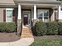 Inviting front porch with brick steps, white columns, and decorative shrubbery enhances curb appeal at 10000 Dressage Ln, Midland, NC 28107
