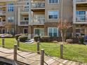 Exterior view of condo building with balconies and manicured lawn, accessible via wooden boardwalk at 103 Pier 33 Dr # 207, Mooresville, NC 28117