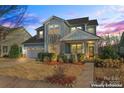 Charming two-story home with light blue siding, a manicured front yard, and inviting front porch at dusk at 12018 Grey Partridge Dr, Charlotte, NC 28278