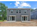 Backside of a gray two-story townhome featuring sliding glass doors and concrete patios on a sunny day at 507 Bowman Rd, Charlotte, NC 28217