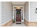 View of the front door with a dark finish, a wreath, sidelights and brick accents at 531 Red Wolf Ln, Clover, SC 29710