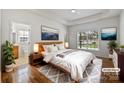 Sun-filled main bedroom features a tray ceiling, wood floors, ensuite bathroom and neutral decor at 7214 Hathaway Ct, Harrisburg, NC 28075