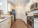 Modern kitchen features stainless steel appliances, white cabinetry, granite countertops, and hardwood floors at 8418 Loxton Cir, Charlotte, NC 28214