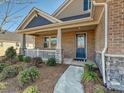 Close up of a well-manicured front yard with a covered porch and a blue front door at 9432 Liberty Hill Dr, Mint Hill, NC 28227