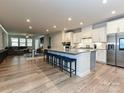 Open-concept kitchen featuring a large island with seating, stainless steel appliances, and hardwood floors at 9432 Liberty Hill Dr, Mint Hill, NC 28227