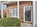 Close-up of the front entrance with a storm door, brick facade, and manicured shrubbery at 3099 Windsor Trace Dr, Fort Mill, SC 29707