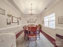 Elegant dining room featuring a tray ceiling, a chandelier, and a large window at 4032 River Falls Dr, Lowell, NC 28098