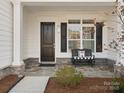 Inviting front porch with stone base, bench seating, and a stylish black front door at 82116 Standing Oak Dr, Charlotte, NC 28278