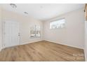 Bright living room features beautiful laminate floors, a large window, and neutral walls creating an open space at 11029 Ardglass Ct, Charlotte, NC 28213