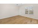 Bright living room features beautiful laminate floors, a large window, and neutral walls creating an open space at 11029 Ardglass Ct, Charlotte, NC 28213