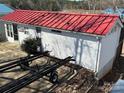 Exterior view of home with bright red roof, showcasing its lakeside charm and boat trailer at 117 Badin Lake Cir, New London, NC 28127