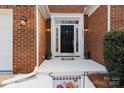 Inviting front porch with decorative accents, potted plants, and a charming black front door at 16032 Hollingbourne Rd, Huntersville, NC 28078