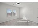 A bright bedroom featuring neutral carpet, two large windows, and a ceiling fan at 3012 Seville St, Charlotte, NC 28214