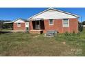 A view of the back of the single-story brick house with a covered area and an overgrown yard at 4521 Fallston Rd, Shelby, NC 28150