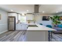 Bright kitchen with white cabinets, stainless steel appliances, laminate floors and a spacious island with a quartz countertop at 8208 Doverdale Ln, Charlotte, NC 28217