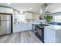 Modern kitchen boasts white cabinetry, stainless steel appliances, quartz countertops, and a sleek range hood at 8208 Doverdale Ln, Charlotte, NC 28217