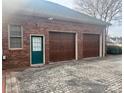 Attached two-car garage with wooden doors and brick exterior with stained door at 1217 12Th Fairway Nw Dr, Concord, NC 28027
