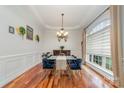 Elegant dining room boasts hardwood floors, detailed trim, modern chandelier, and large window with natural light at 3046 Denali Way, Rock Hill, SC 29732