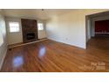 Living room featuring hardwood floors, a brick fireplace, and bright windows, ready for cozy gatherings and relaxation at 7201 Gilead Rd, Huntersville, NC 28078