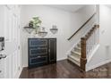 Inviting entryway with sleek black cabinet, modern decor, and staircase with carpeted steps and wooden railing at 9804 Ainslie Downs St, Charlotte, NC 28273