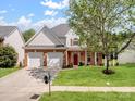 Charming two-story home featuring a manicured lawn, two-car garage and a classic brick and siding facade at 10032 Montrose Nw Dr, Charlotte, NC 28269