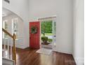 Inviting foyer with hardwood floors, an open red front door with wreath and view to the outside at 10032 Montrose Nw Dr, Charlotte, NC 28269