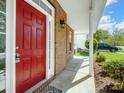Close-up of the red front door, showing the brick facade and covered porch at 10032 Montrose Nw Dr, Charlotte, NC 28269