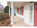 Spacious covered front porch featuring classic columns, red shutters and an inviting entryway at 10034 Bishops Gate Blvd, Pineville, NC 28134