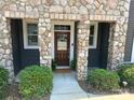 Charming front entrance with stone pillars, a wood door, and manicured bushes and a small garden at 1019 Archibald Ave, Fort Mill, SC 29708
