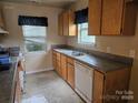 Outdated kitchen featuring wooden cabinets, a double basin sink, and a window for natural light at 5315 Airport Dr, Charlotte, NC 28208