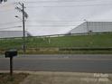 View from the road of a commercial building with utilitarian design, set behind a fence with a grassy hillside at 5315 Airport Dr, Charlotte, NC 28208