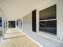 Long covered porch with new decking, white pillars, siding and trim, and black shutters at 704 Mill St, Albemarle, NC 28001