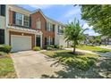 Well-maintained brick townhome featuring an attached garage, lush lawn, and mature landscaping at 140 N Arcadian Way, Mooresville, NC 28117