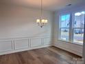 Sunlit dining room with hardwood floors, elegant chandelier, and large windows offering neighborhood views at 15238 Ravenall Dr, Huntersville, NC 28078