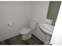 Small, white, half bathroom featuring pedestal sink, toilet, mirror and wood look vinyl flooring at 212 Sugar Hill Rd, Troutman, NC 28166