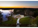 Breathtaking aerial view of a luxury home with a private lakefront, lush greenery, and stunning sunset at 2536 Brawley School Rd, Mooresville, NC 28117