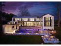 Beautiful backyard featuring an illuminated pool, stone patio, and inviting fire pit area at 2536 Brawley School Rd, Mooresville, NC 28117