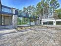 Stunning modern home with a paver driveway, two-car garage, stone accents, and walls of windows at 2536 Brawley School Rd, Mooresville, NC 28117